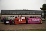En grupp människor framför en buss med banderoller