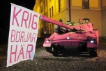 Bild på rosamålad stridsvagn i Umeå med banderoll "Krig börjar här"