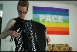 Oscar Schön spelar dragspel framför en regnbågsflagga med texten "PACE"